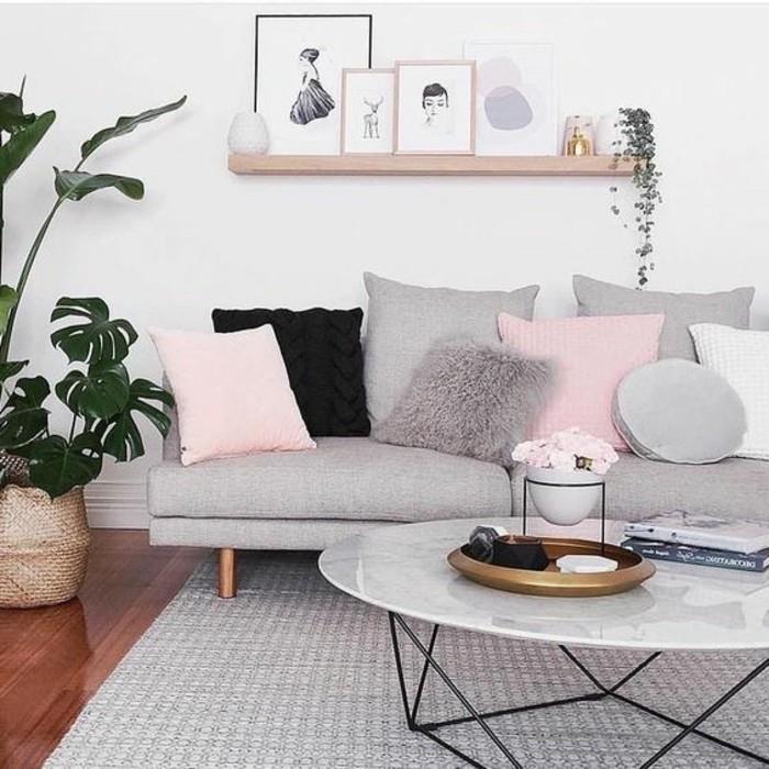 pilka sofa, rožinės pagalvės, marmurinis kavos staliukas, medinė pakabinama lentyna, pilkos svetainės sienos