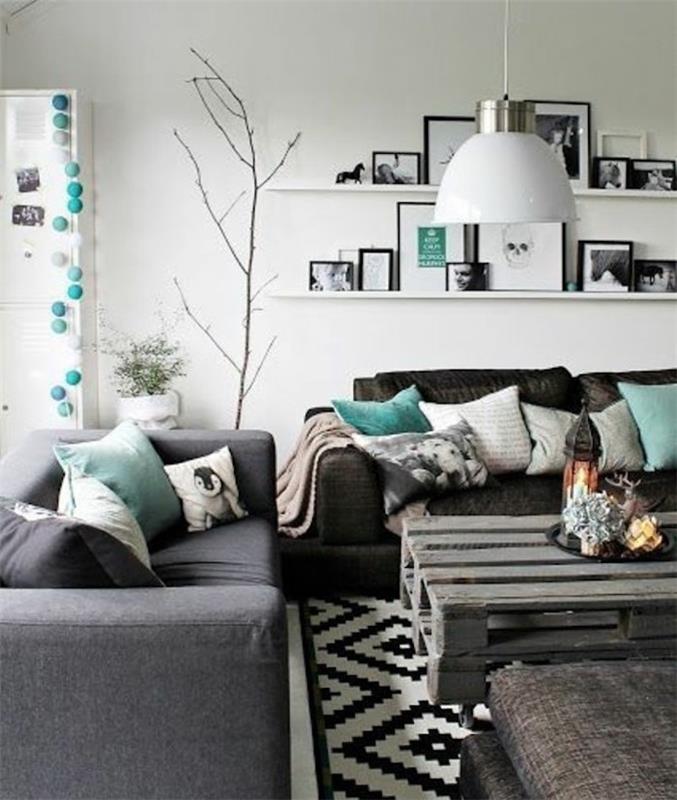 pilkos ir juodos sofos, turkio spalvos pagalvės, medinis padėklų kavos staliukas, akcentuojamos spalvos pilkai