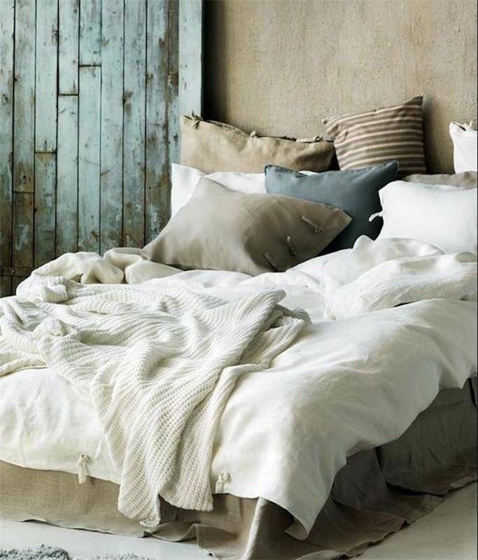 mišja siva barva na stenah spalnice v sivo -beli barvi, pleteni beli plaid, grege blazine, modra in rjava, obrabljena vrata
