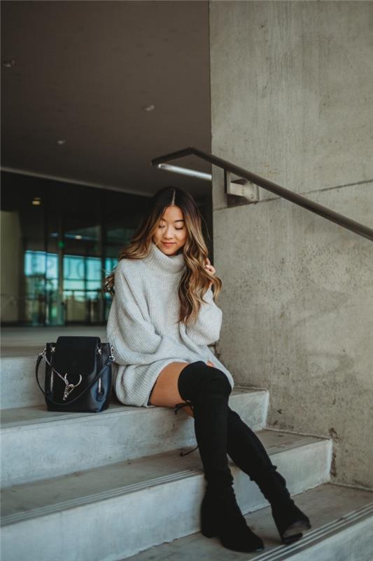 prašmatnus žiemos apranga ilgame megztinyje su moterišku apykakle kartu su juodais batais iki kelių ir juoda kuprine