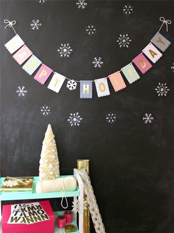 linksmų Kalėdų Kalėdų girlianda iš mažų spausdintų popierinių vimpelių su nelygiu kraštu, uždėta ant šiferio sienos