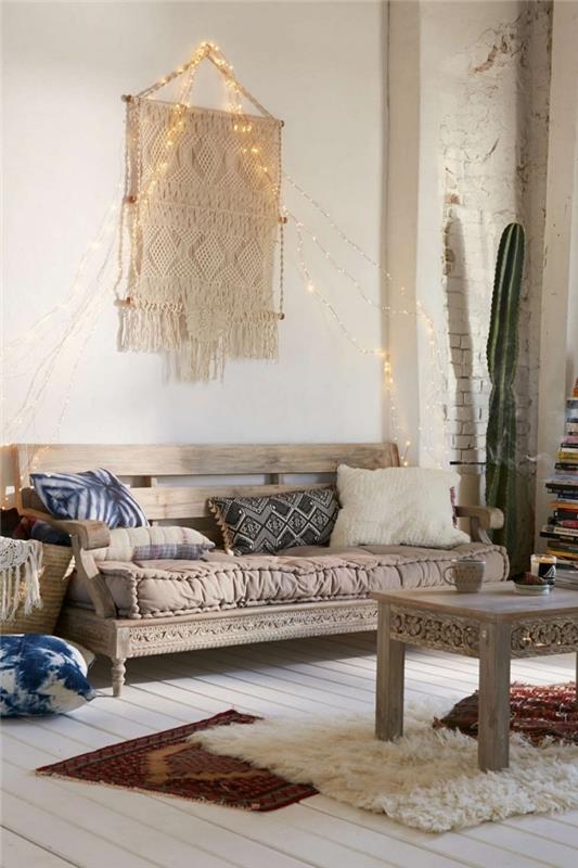 primer stenskega ustvarjanja iz makrame preje, boemsko elegantne dekoracije dnevne sobe z lesenim kavčem in okrasnimi blazinami