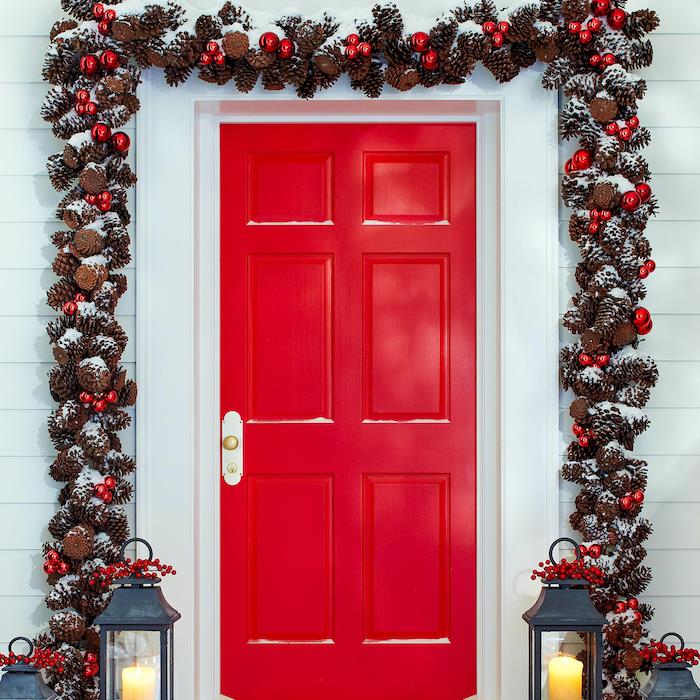 çam kozalakları ve Noel topları ile oluşturulan kapıyı çerçeveleyen Noel gurlande dışında
