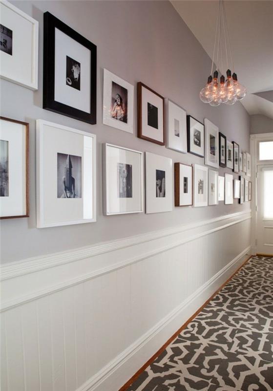 dve vrsti kvadratnih okvirjev, različnih velikosti in barv, ki vsebujejo črno -bele slike, obešene na bledo sivi steni, dekor na hodniku, sive in bele talne ploščice