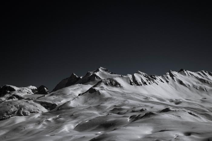 belina skalnatega gorskega grebena, pokritega s snegom, ki izstopa na ozadju črnega neba, najlepše podobe črno -belih gorskih pokrajin