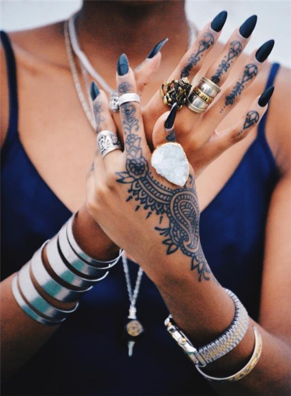 tetovaža s kano, ženska z zapestnico iz zapestnice iz kovinskega nakita in prstani, ženske roke s črnim lakom in začasno tetovažo