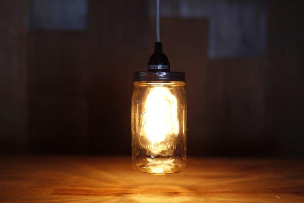 Siyah kablodan sarkan şeffaf bir cam kavanozun içinde parlayan ampulden yapılmış yanan lamba