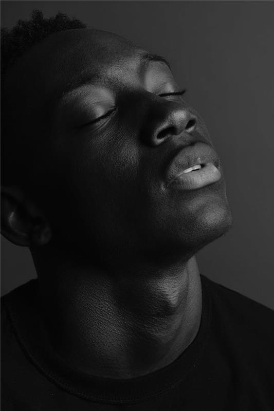 Črno -beli portretni moški, ozadje v dveh barvah, temno izrazna fotografija