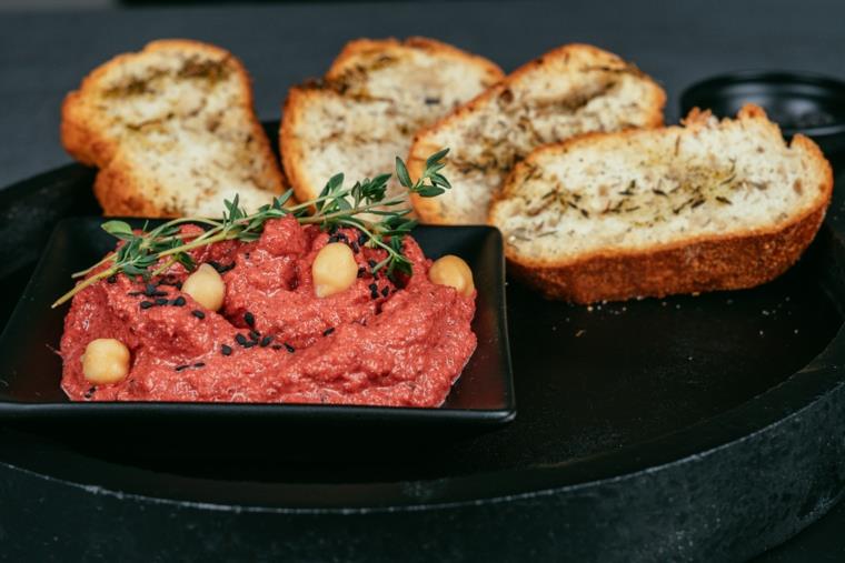 Ricetta hummus, crostini di pane all'olio e timo, ciotolina con hummus alle barbabietole