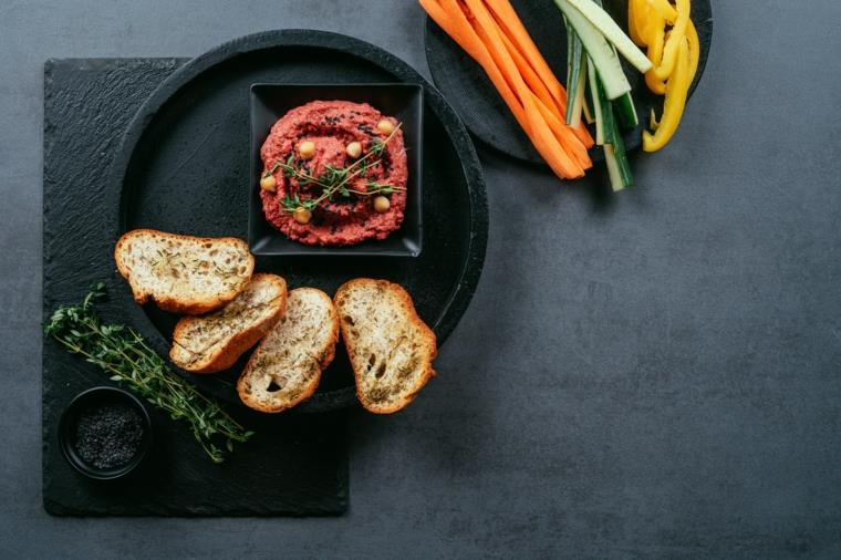 Aperitivo vegetariano, crostini di pane con timo, hummus di barbabietole ir tai