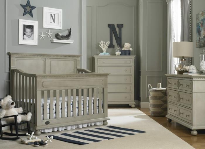 pilka kūdikio lova, pilkas kilimas, mažas dryžuotas kilimas, įrėmintos nuotraukos, pilki vaikų kambario dažai