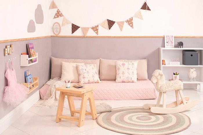 idėja, kaip sutvarkyti mažos mergaitės kambarį, plyteles, apvalų įvairiaspalvį kilimą, rausvą čiužinį, pagalvėles, mažą saugyklą, baltą ir pilką sieną, vimpeles, Montessori lovelę
