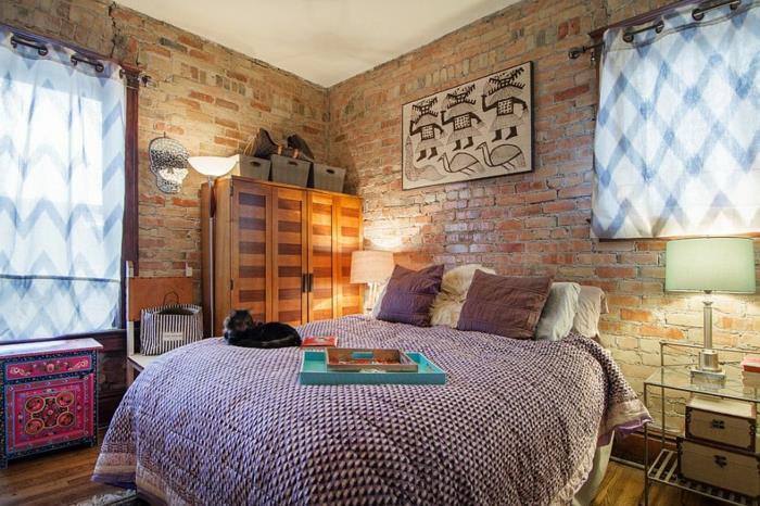 pisana dekoracija spalnice, originalna lesena omara, vintage kovčki, stena iz rdeče opeke