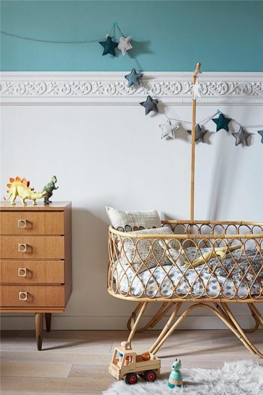 beyaz duvar frizleri ile mavi ve beyaz bebek odası dekoru Dokuma bastonlarda bebek yatağı ve açık kahverengi mobilyalar