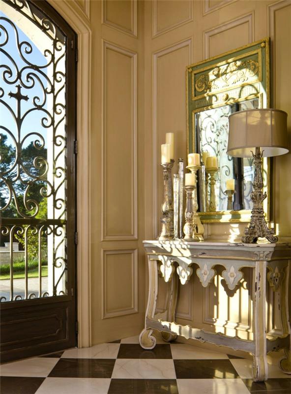 kaip papuošti didelio namo įėjimą, prašmatnią namo įėjimo deko idėją su dideliu veidrodžiu, abažūriu, metaliniais žvakidėmis