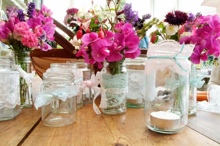 ideja poročne dekoracije, osebni stekleni kozarci s čipko, svečniki in lonci za rože, napolnjeni s šopki