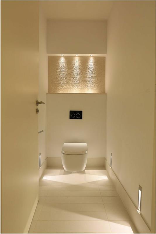 kreminės spalvos tualeto dekoras, baltas tualetas, įleidžiami prožektoriai virš sienos nišos