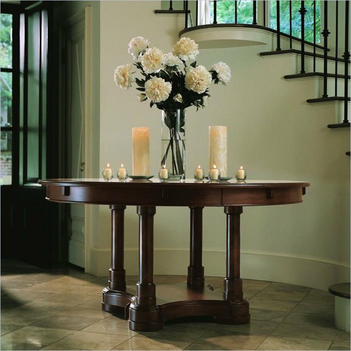paprastas ir stilingas įėjimas, medinis stalas, baltos žvakės, bijūnų puokštė šalia elegantiškų laiptų