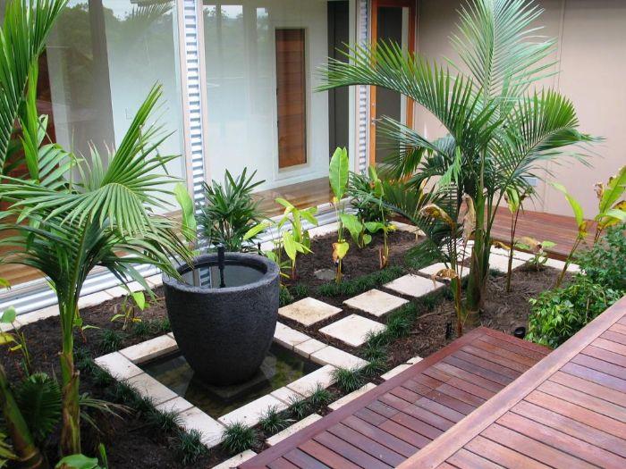 ideja za razvoj majhnega vrta v velikosti 20 m2 z leseno teraso s ploščami sredi zelenih rastlin