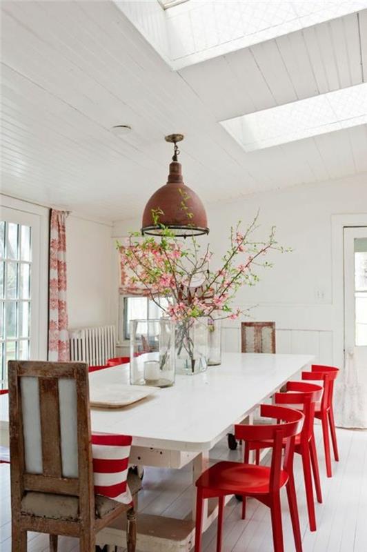 Sala da pranzo con un tavolo grande di colore bianco e sedie rosse