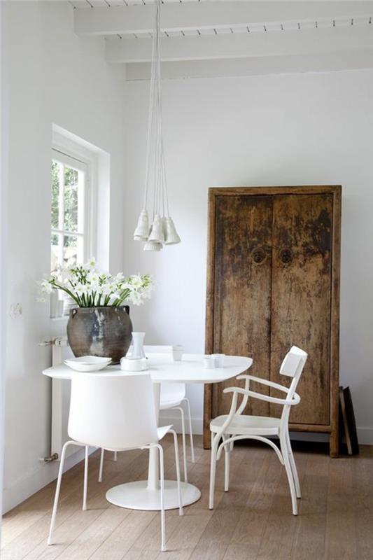 Piccola sala da pranzo con un tavolo e sedie bianche, armadio rustico di legno