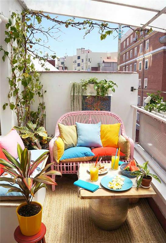 pavyzdys mažam ilgam balkonui, spalvingai terasai su rožine pinta sofa ir gebenės šakomis