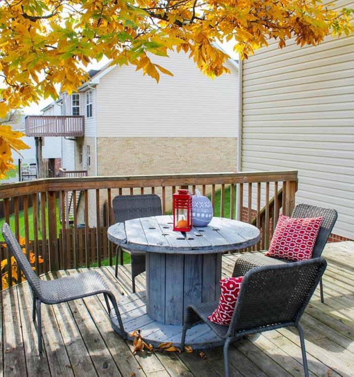 Tik ağacından teras düzeni, griye boyanmış makaralı masa, rattan sandalyeler, sonbahar manzarası