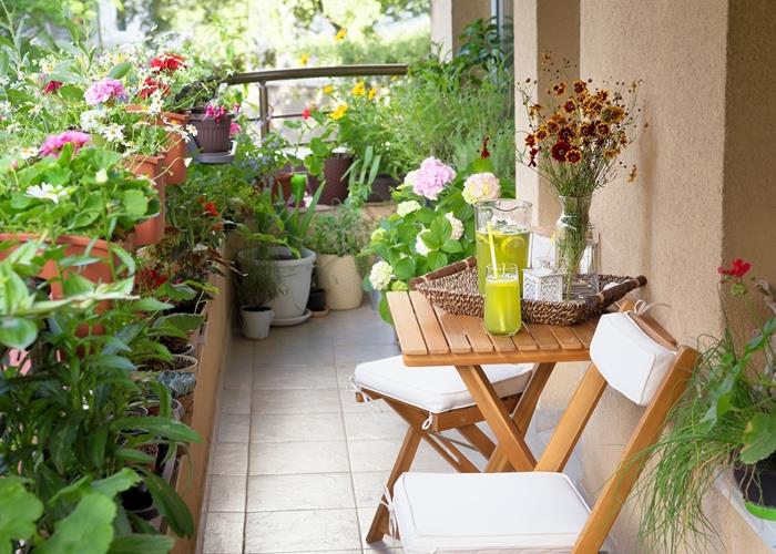 ideja vetrič pogled rastlinska dekoracija majhen balkon s cvetjem cvetlični lončki terakota pohištvo lesena mizica zložljiv stol