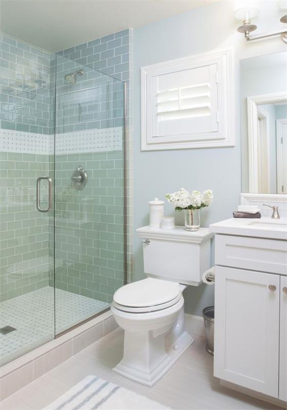 pastelinės žalios plytelių dušo kabinos idėja, vandens atspalvis, mėlynas vonios kambarys su balta vonios spintele ir baltu tualetu