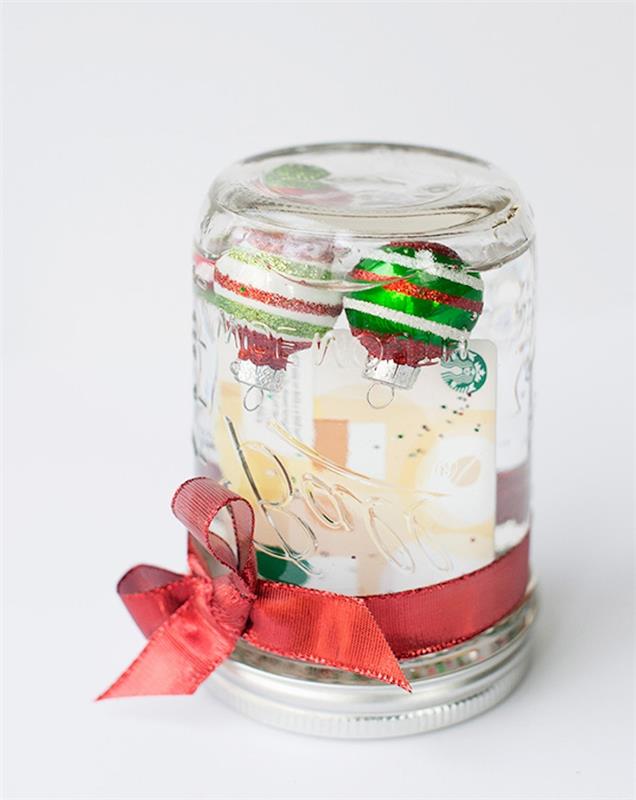 Ideja za božično darilo za 15 -letnega najstnika, steklena snežna krogla v kozarcu, okrašena z rdečim trakom in božičnimi kroglicami v notranjosti