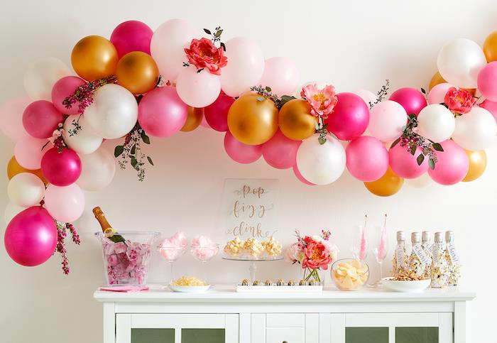 lok iz belih, zlatih in roza balonov nad belim bifejem s sladkarijami, bombažem, temo cirkuske zabave