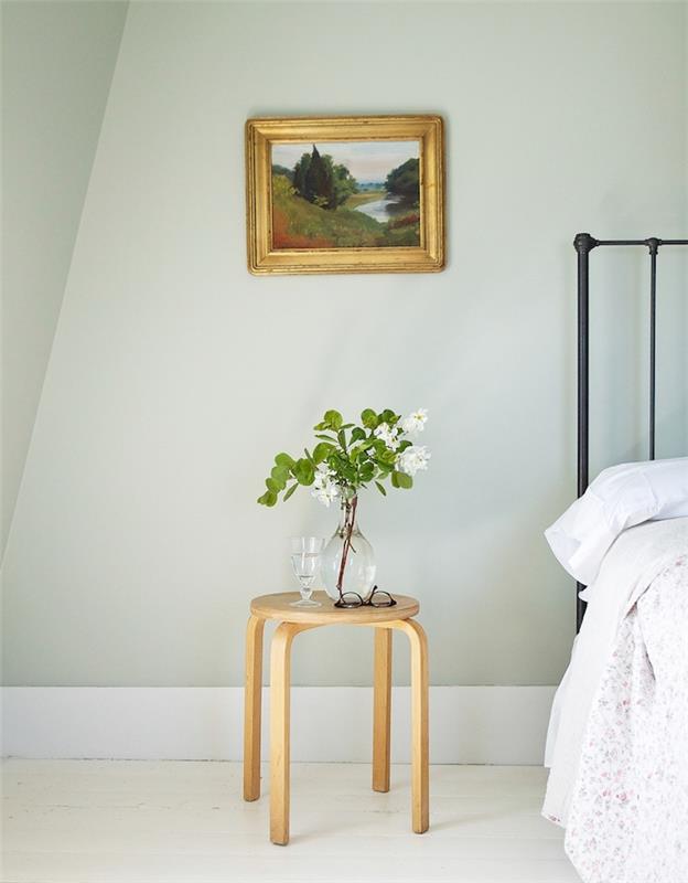 dekor za spalnico za odrasle sivo-zelene stene, vintage črna kovinska postelja, umazano bela talna obloga, lesena nočna omarica, minimalističen slog