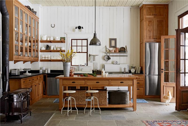 eleganten model podeželske kuhinje, osrednji leseni otok in rjava lesena kuhinjska fasada, belo opaž, talna obloga iz cementnih ploščic, belo posodo, leseni predalnik, industrijska viseča svetilka