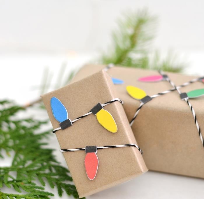 Kalėdų dovanų paketas, idėja apie mažas kraftpopieriaus dėžutes, papuoštas šviesiu girliandos raštu juodai balta eilute su spalvotų žibintų raštu