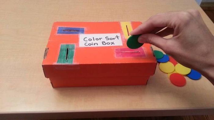 Bir kreşte renkleri öğrenmek için Montessori eğitici oyunu, bir karton kutunun ilgili yuvalarına renkli paralar yerleştirin, montessori kendin yap malzemesi