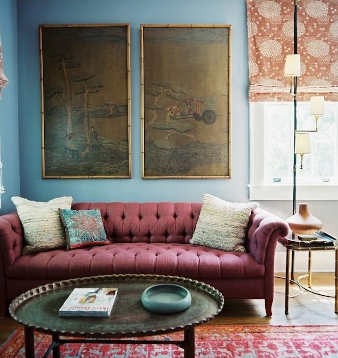 bordo spalvos sofa mėlyname miegamajame, dėvėtas rytietiško kilimėlio vintažinis metalinis kavos staliukas, japoniškos dekoratyvinės plokštės