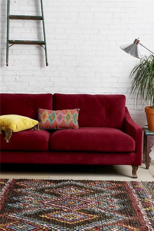 spalvų asociacija, bordo sofa baltame fone, plytų siena, spalvotas kilimas, sienų deko svarstyklės