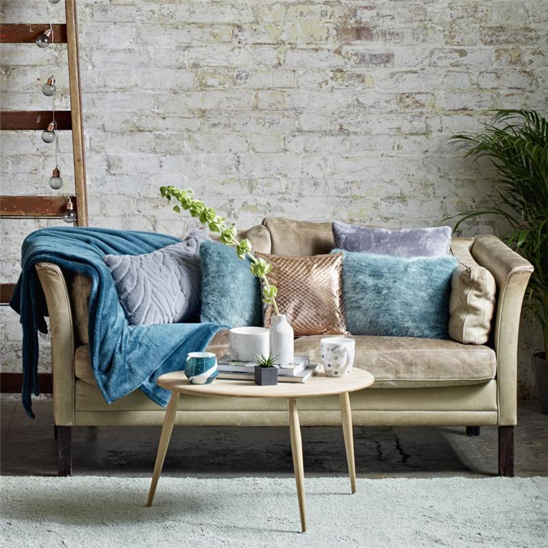 bej kanepe renk kombinasyonu, pembe, mavi ve leylak rengi kırlentlerle süslenmiş, mavi battaniye, gri halı, soluk beyaz duvar