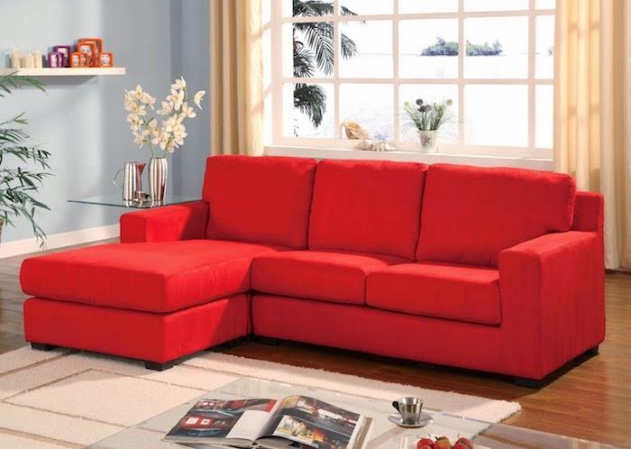 raudona vermiliono sofa neutralioje svetainėje, smėlio spalvos kilimas ir užuolaidos, šviesiai mėlyna siena, rudas parketas, stiklinis kavos staliukas