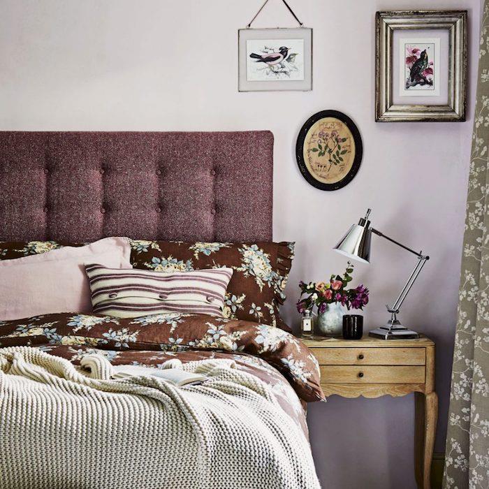 ideja za okrasitev spalnice za odrasle, vijolično rožnato stensko poslikavo, bordo oblazinjeno vzglavje, posteljnina, rjava s cvetličnimi vzorci, svetlo siva odeja, vintage lesena nočna omarica, okras kinezerja