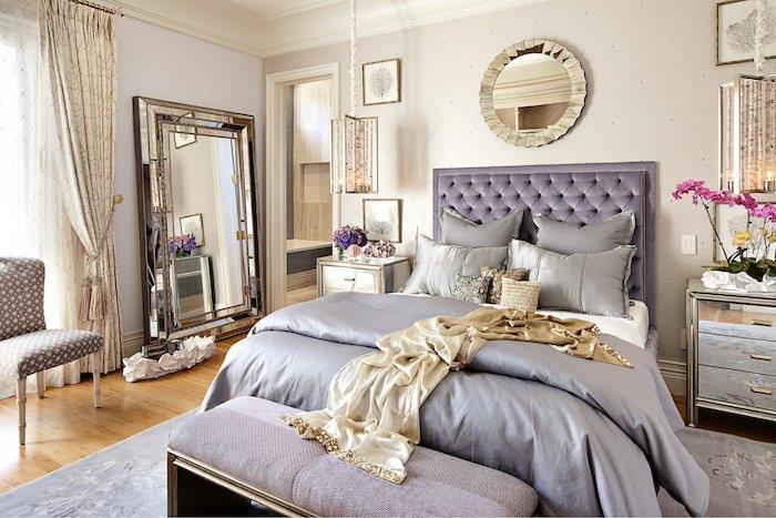 Dekor glavne spalnice v baročnem slogu, vijolično posteljno vzglavnik, siva kovinska komoda, veliko ogledalo, lahek parket, oblikovalske vzmetenja