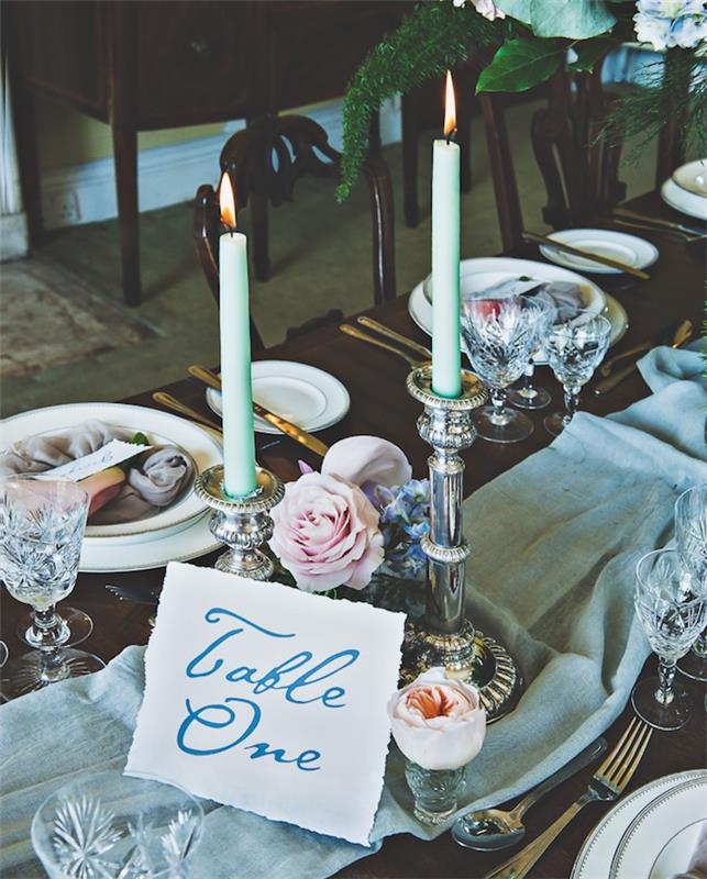 kaimiškos prašmatnios vestuvės, šviesiai pilko audinio stalo bėgikas, gėlių kompozicijos, sidabrinės žvakidės, medinis stalas