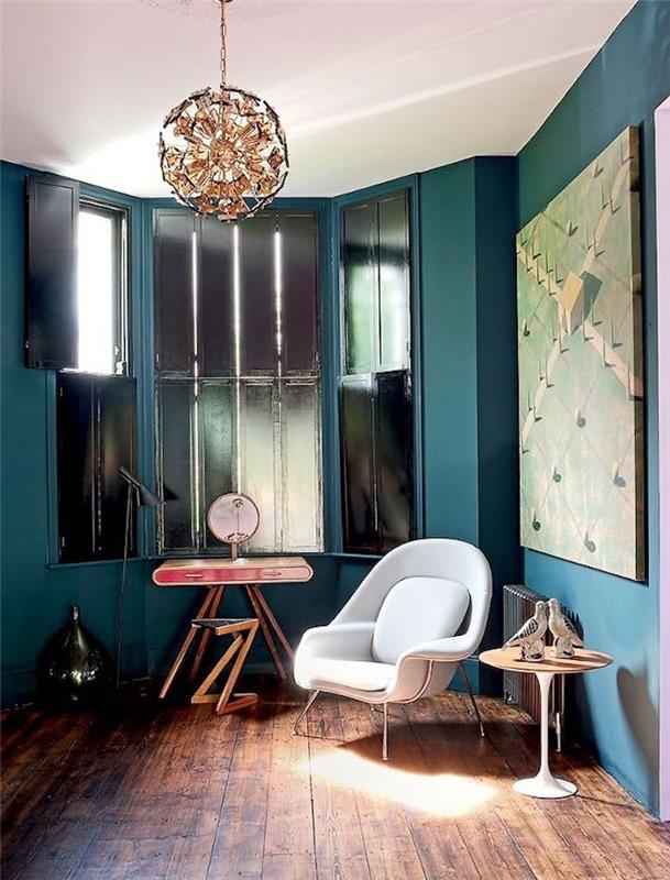 anties mėlynos svetainės dekoro idėja, naftos atspalvis, rudas parketas, beveik balta kėdė, originali pakabinama šviesa, langai su juodomis langinėmis ir senovinio dizaino stalas