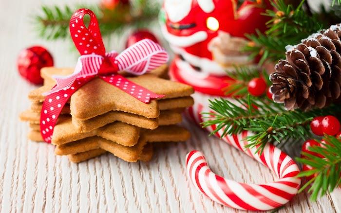 gurmaniški kalėdiniai tapetai, kalėdiniai sausainiai, papuošti raudonomis ir baltomis juostelėmis, pušies šakomis, bugieniais, kankorėžiais, cukranendrėmis ir Kalėdų Senelio figūrėlėmis