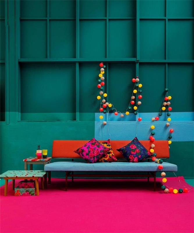 benzininis mėlynas svetainės modelis, naftos ir povo atspalvio sienų dažai, dizainerio mėlynos ir raudonos spalvos sofa, fuksijos kilimas, spalvinga šviesi girlianda