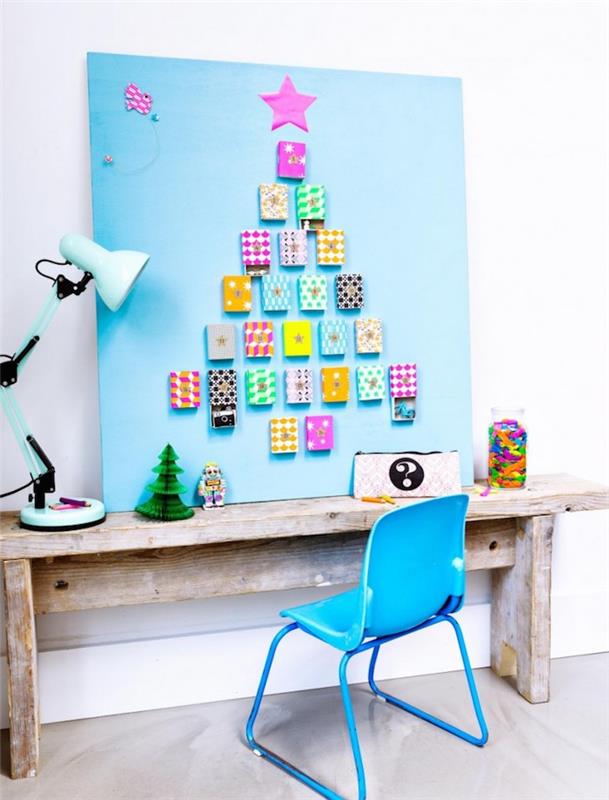 Çocuğun masasının içinde sürprizlerle dolu renkli kutularla köknar ağacı deseni ile süslenmiş mavi bir panel fikri