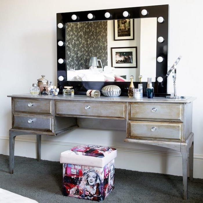 atlaikiusio baldo pavyzdys, moteriškas miegamojo tualetinis staliukas, pilki dažai ir medžio dėmės, suteikiančios vintažinės išvaizdos, pop meno išmatos ir veidrodis su žibintais