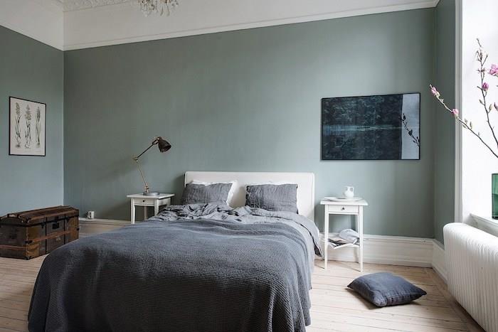stene v barvi verdigris v oblikovalski spalnici za odrasle, parket iz svetlega lesa, sivo posteljno perilo, starinska skrinja za shranjevanje, skandinavska spalnica