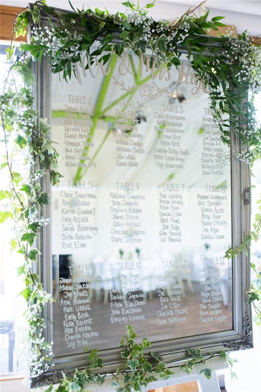 „pasidaryk pats“ vestuvių veidrodinis stalo planas su skaičių lentelėmis ir svečių vardais, parašytais baltu veltiniu stiklui, žaliai girliandai