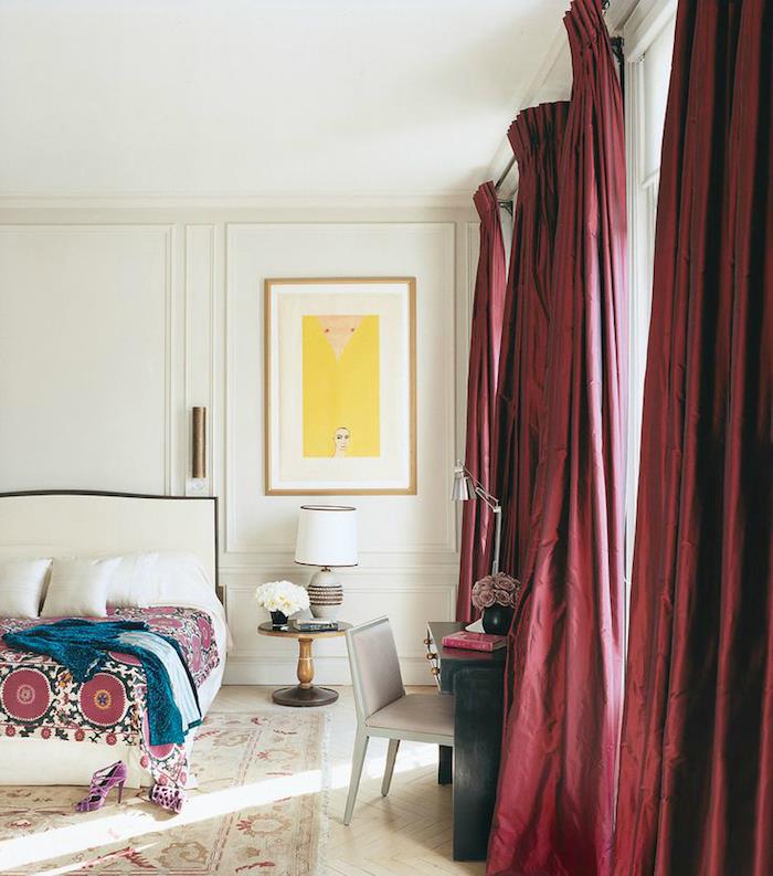 bordo zavese v beli spalnici, oblikovalec, belo posteljnino in odejo z orientalskim vzorcem, izrabljena preproga, beljen parket